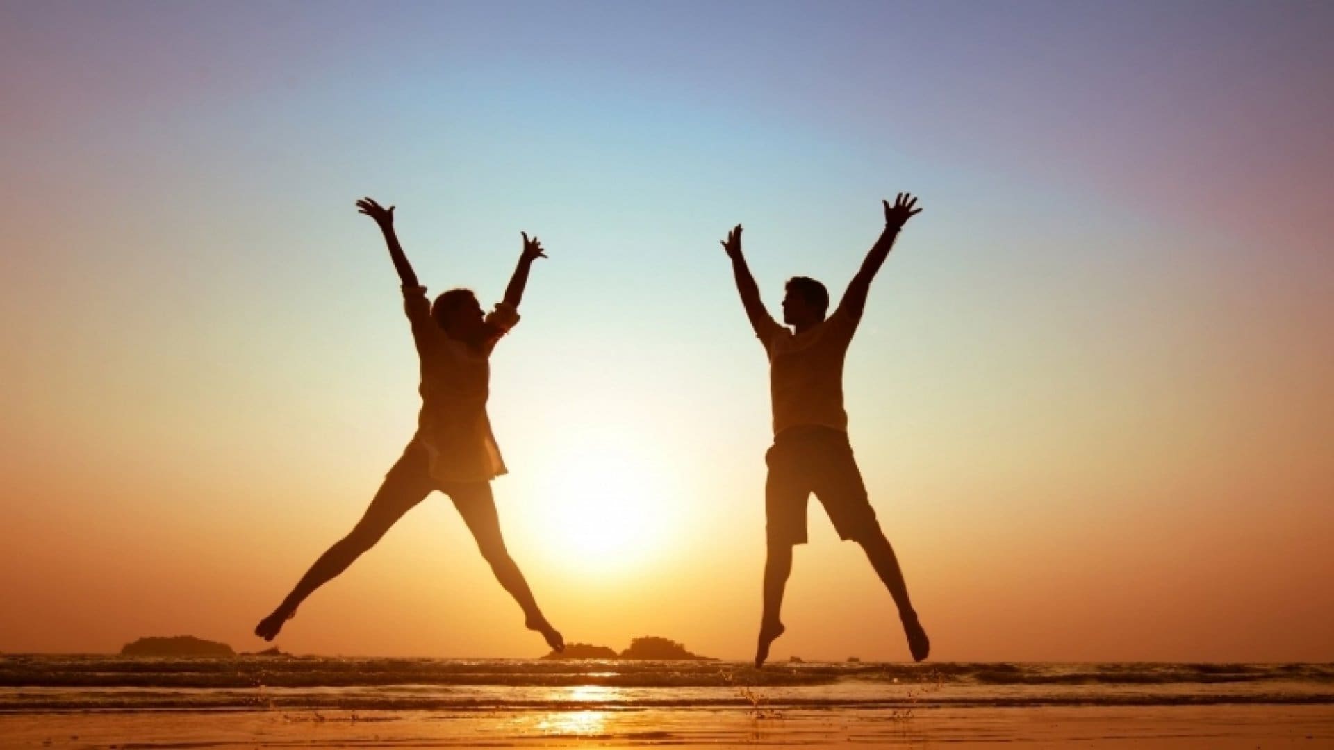 two people jumping on the beach