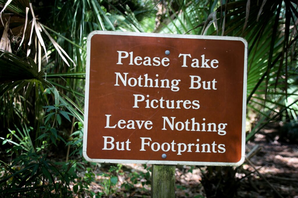 A sign reading "Please Take Nothing But Pictures Leave Nothing But Footprints"